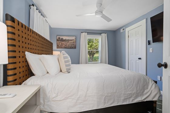 Main floor bedroom with a king bed, woven leather headboard and blue-grey walls.