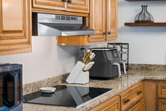 Granite counter and cooktop with knife block and air fryer.