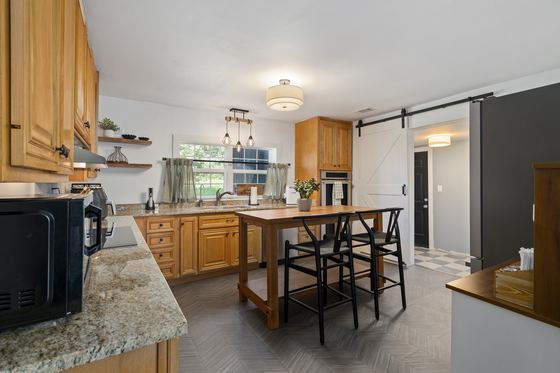 Kitchen island with stools, looking through to the sliding barn door.