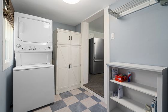 Laundry area with a stacked washer and dryer and checkerboard floor.