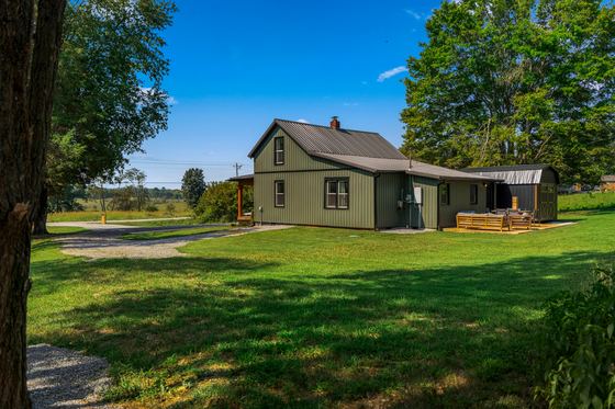 The property seen across the lawn, trees on both sides.