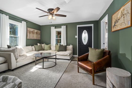 Living room with sage green walls, a deep sectional and a leather armchair.