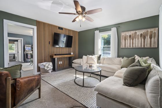 Living room from the far corner, television mounted on a slatted wood wall.