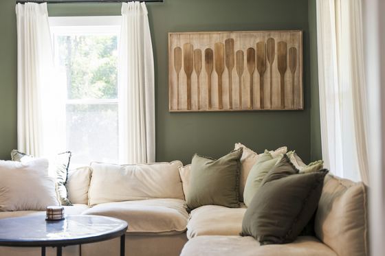 Sofa beneath a bright window with oar artwork above.