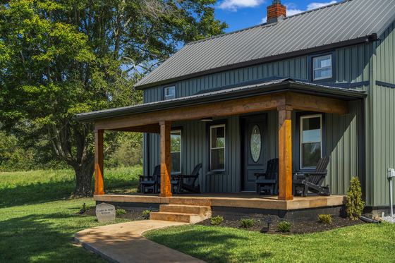 The covered front porch with cedar posts and black Adirondack chairs.