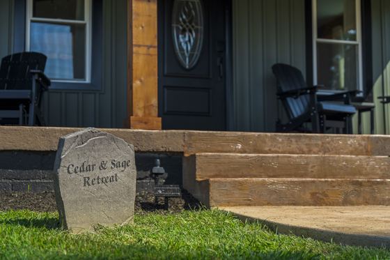 Engraved stone marker at the foot of the porch steps reading Cedar and Sage Retreat.